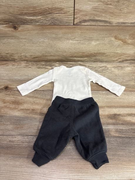 Top-down view of Just One You two-piece bodysuit and pants set showing a white long-sleeve bodysuit and black pants on wood flooring