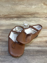 Brown toddler ballet flats with elastic straps on a wood background