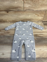 Gray knit baby romper with sheep pattern and snap buttons, laid flat on wood floor