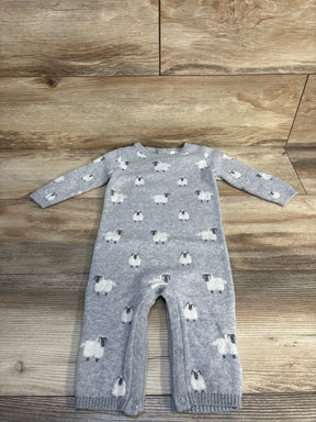 Gray knit baby romper with sheep pattern and snap buttons, laid flat on wood floor