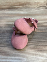 Pink suede baby Mary Jane shoes with strap on wood floor, toddler footwear