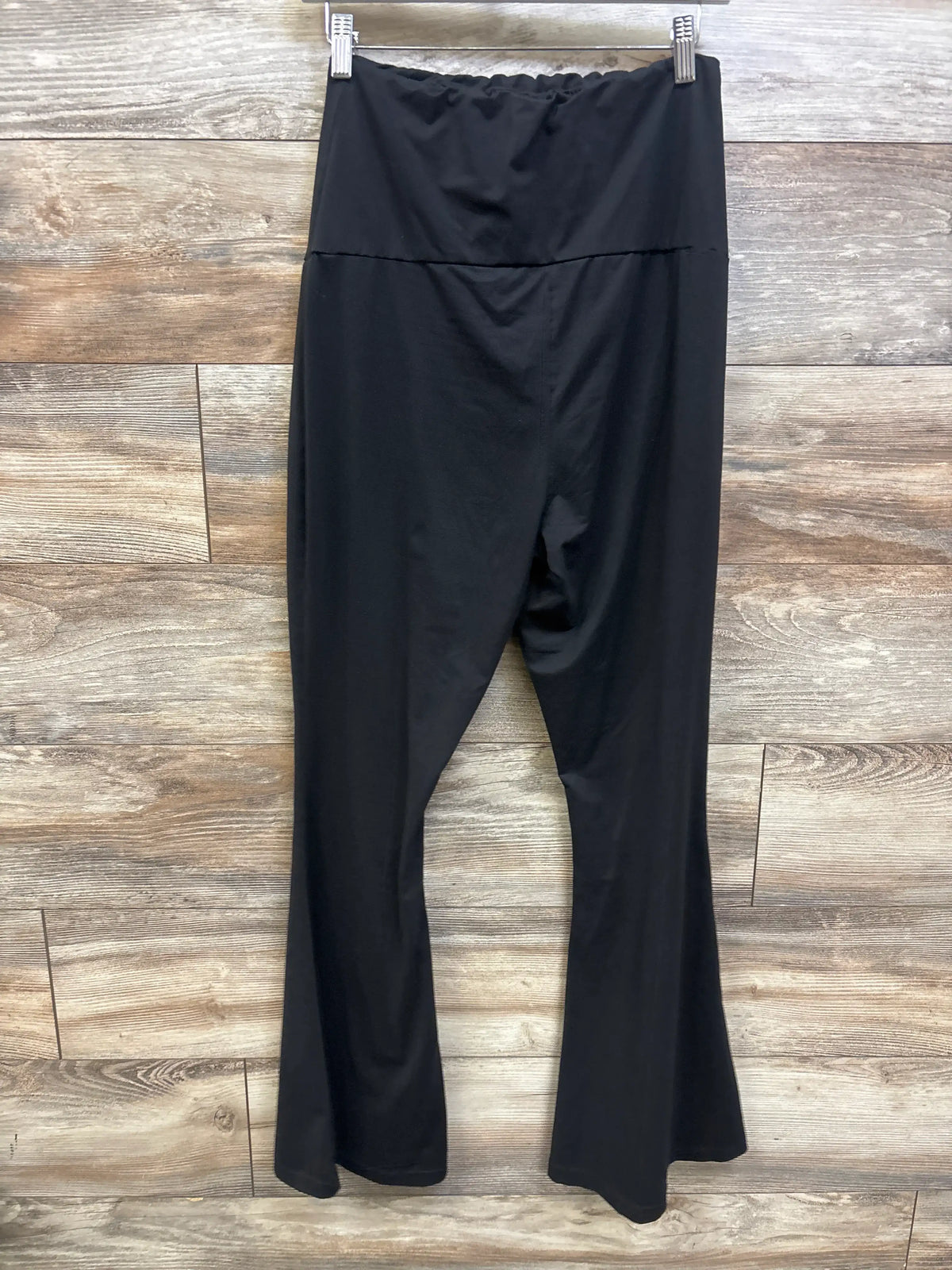 Black maternity flared leggings by Me n Mommy To Be displayed against a wood-panel background