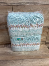 Front view of Pampers size 1 60-count sleeve showing stacked light-blue printed diapers in clear plastic on a wood background