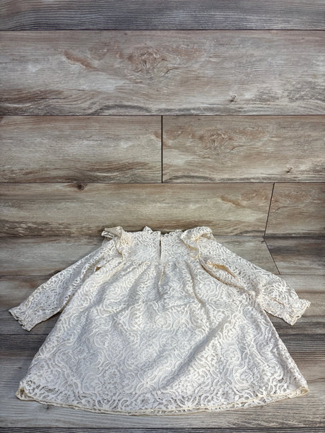 Ivory lace long sleeve baby dress with ruffle shoulders on wood background