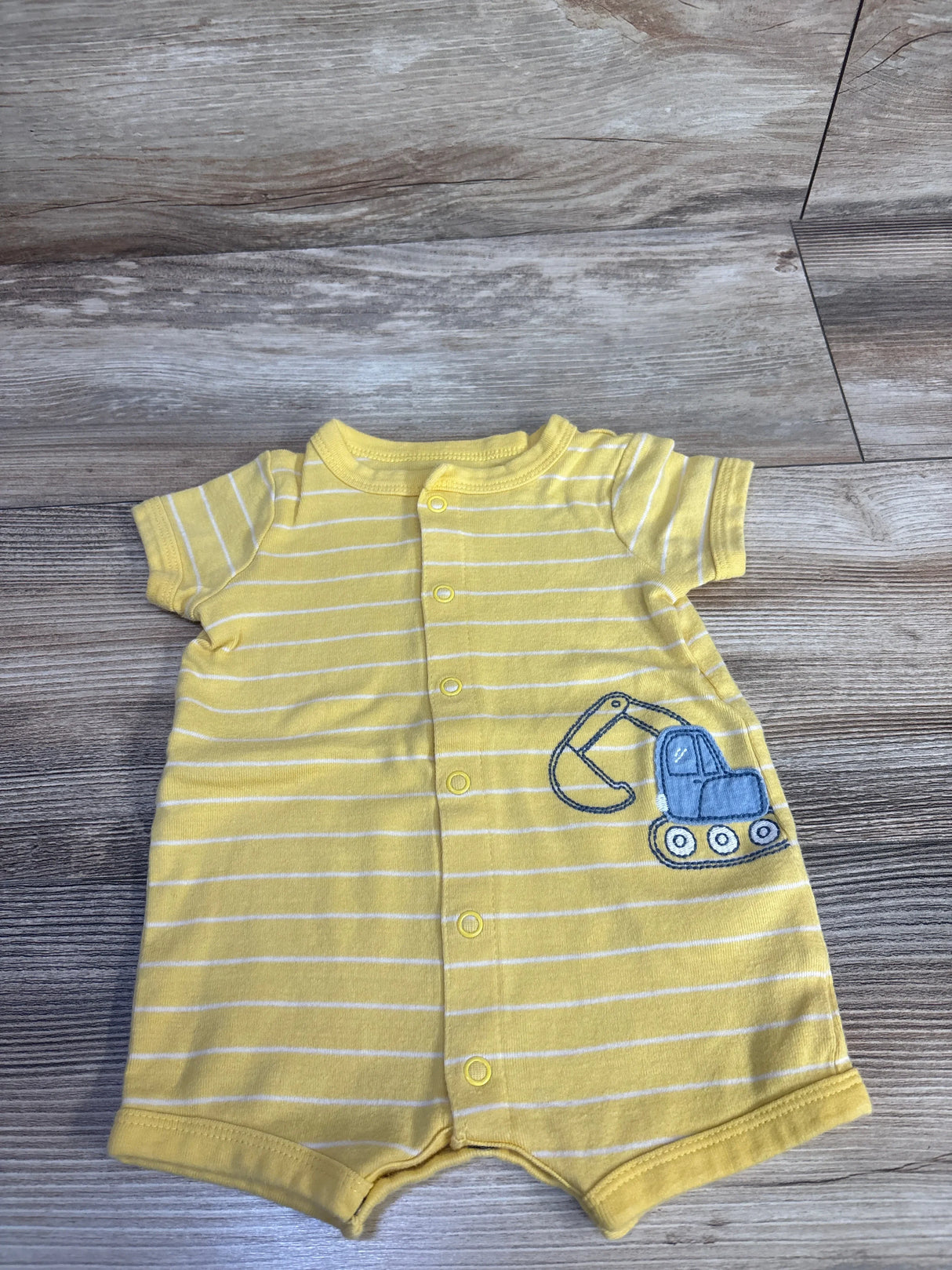 Front view of Carter's yellow striped shortie romper size 3M with blue excavator applique and snap front closure laid flat