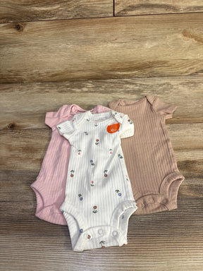 Flat lay of three preemie ribbed bodysuits, white floral, pale pink, and mauve, showing short sleeves and snap crotch on wood background