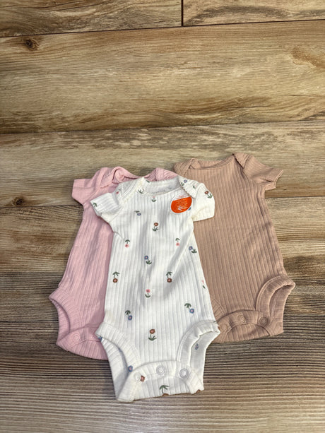Flat lay of three preemie ribbed bodysuits, white floral, pale pink, and mauve, showing short sleeves and snap crotch on wood background
