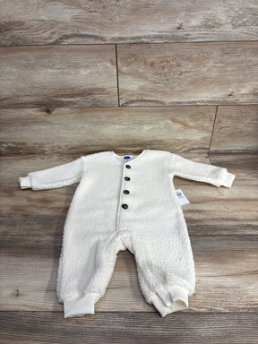 White fleece baby romper with front buttons on wood background, cozy infant clothing