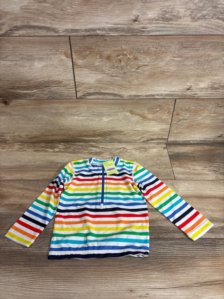 Flat lay of baby long-sleeve rash guard, rainbow stripes, front quarter-zip, size 12-18 months on wood floor