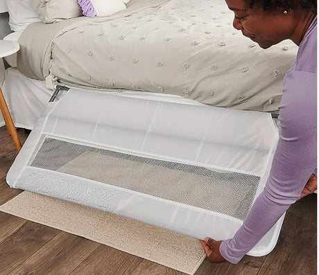 Angled view of Regalo Guardian swing-down bedrail in white showing lowered mesh panel and metal mounting bar on a bed