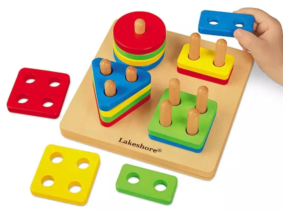 Angled top view of Lakeshore Sort-A-Shape activity board showing four colorful shape stacks and a child's hand on white