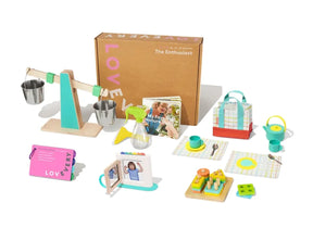 Front of Lovevery Enthusiast Play Kit with balance scale, tea set, stacking toys and board book on white background