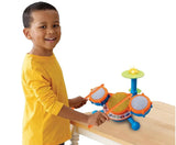 Smiling child in yellow shirt playing with colorful toy drum set on table