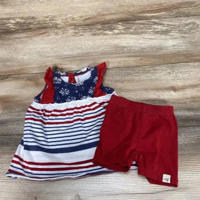 Flat lay of Burt's Bees baby 2-piece showing navy star yoke striped tunic and red elastic-waist shorts on wood background