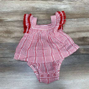 Flat-lay of red and white striped newborn romper with tassel-trim shoulder ruffles and snap crotch on wood background