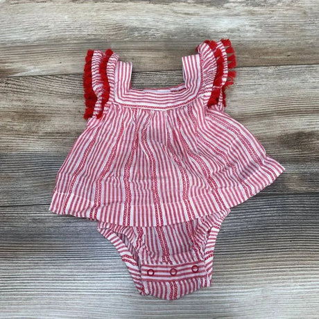 Flat-lay of red and white striped newborn romper with tassel-trim shoulder ruffles and snap crotch on wood background