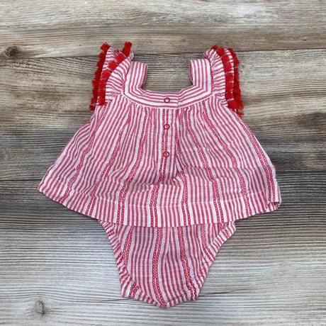 Flat lay of Cat and Jack red-and-white striped newborn romper with tassel-trim ruffled sleeves on wood background