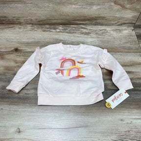 Flat-lay front view of pink Cat & Jack baby sweatshirt (6–9m) showing rainbow-and-cloud print and ruffle shoulders on wood floor