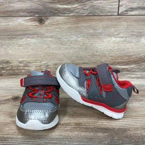 Front and side view of Athletic Works toddler sneakers showing gray mesh upper, red accents, hook-and-loop strap, and white sole on wood floor