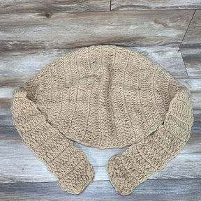 Top-down view of beige hand-knitted newborn hammock showing chunky ribbed crochet texture and straps on wood