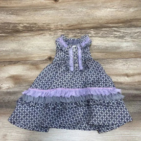 Top-down view of grey 6-month ruffle dress with navy geometric print and lilac tulle trim, sleeveless, flat-lay on wood background