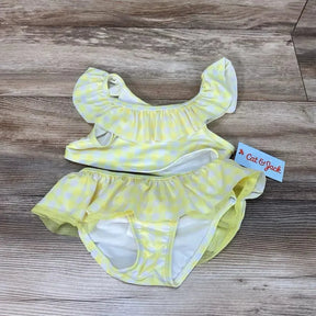 Top-down view of toddler yellow gingham 2-piece bikini set showing ruffle off-shoulder top and skirted bottoms on wood floor background