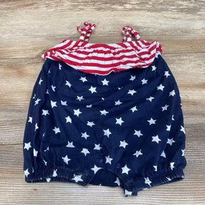 Flat lay of baby shortie romper showing navy star print bottom and red-and-white striped ruffle top with tie straps on wood