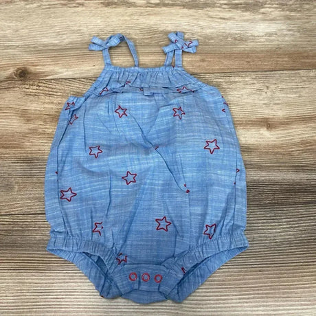 Flat lay of blue chambray romper (0-3M) with red star embroidery, tie straps, ruffle top and snap crotch on wood
