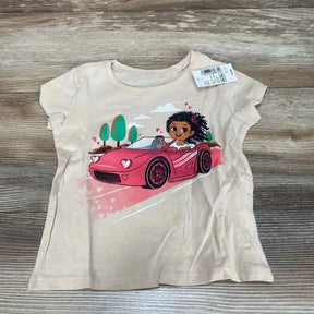 Flat-lay of beige Children's Place toddler graphic tee size 18-24 months showing girl driving pink car graphic on gray wood floor