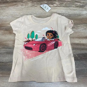 Flat lay of beige Children's Place short-sleeve graphic t-shirt, size 18–24 months, showing pink convertible and girl illustration on wood surface
