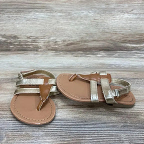 Overhead view of toddler gold Zoe & Zac sandals showing metallic straps, thong front and velcro ankle strap on wood