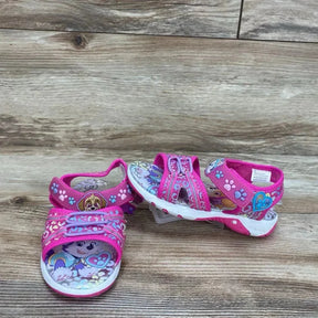Front and side view of pink Paw Patrol toddler ankle-strap sandals showing character print, double velcro straps and white treaded sole on wood background