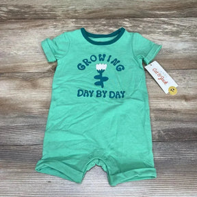 Flat-lay of green Cat & Jack romper saying Growing Day By Day with flower graphic, snap crotch and tag on wood background