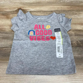 Flat lay gray Okie Dokie 3M baby shirt with ALL GOOD VIBES pink text, rainbow and heart, ruffle sleeves on wood background