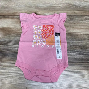 Front view of Okie Dokie bodysuit showcasing pink ruffle sleeve with Bloom daisy floral graphic and hangtag on wood plank floor