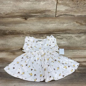 Flat lay of white Minnie floral henley dress size 12 months with ruffled sleeves and gathered skirt on wood background