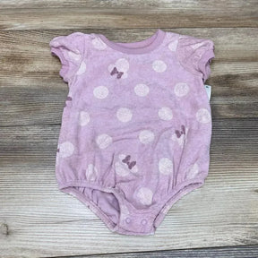 Flat lay of purple Minnie Mouse terry romper 0-3M showing white polka dots, bow motifs, puff sleeves and crotch snaps on wood background