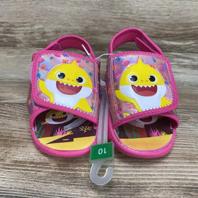 Front view of Pinkfong Baby Shark water sandals 10C with pink velcro character straps and illustrated insole on wood floor