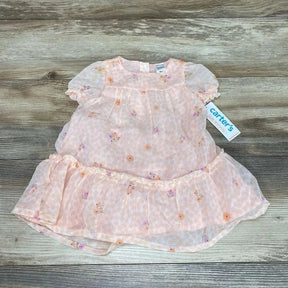 Flat lay of pink two piece floral baby dress and bloomers showing puff sleeves and ruffled hem on light wood background