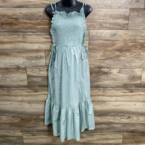 Front view of green Asos maternity smocked maxi dress with tie shoulder straps and ruffle hem on mannequin, wood background