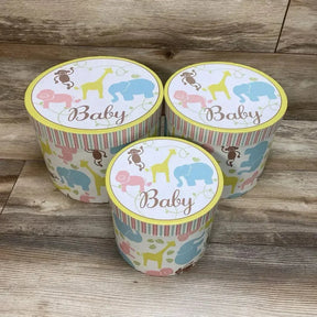 Front view of 3-piece Enchante Baby nesting trunks with pastel animal print and 'Baby' lids on wood floor