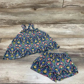 Flat lay of baby sleeveless top and shorts with multicolored floral print and elastic-waist, on wood background