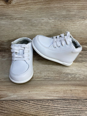 Front and side view of white baby walking shoes showcasing lace-up closure, rounded toe, and padded ankle collar on wood background