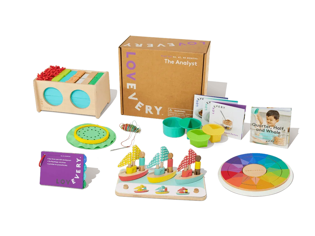 Colorful wooden toddler learning toys, activity cards, and game pieces arranged by a cardboard box.
