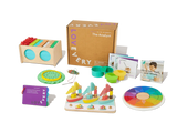 Colorful wooden toddler learning toys, activity cards, and game pieces arranged by a cardboard box.