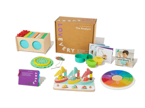 Colorful wooden toddler learning toys, activity cards, and game pieces arranged by a cardboard box.