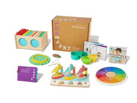 Colorful wooden toddler learning toys, activity cards, and game pieces arranged by a cardboard box.