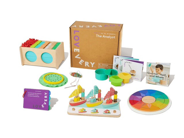 Colorful wooden toddler learning toys, activity cards, and game pieces arranged by a cardboard box.