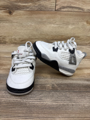 Angled view of Air Jordan 4 Retro OG TD White Cement sneakers showcasing white leather and black detailing on a wood grain surface