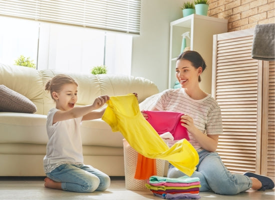 Parents sorting clothing at home with child to sell at a consignment sale 